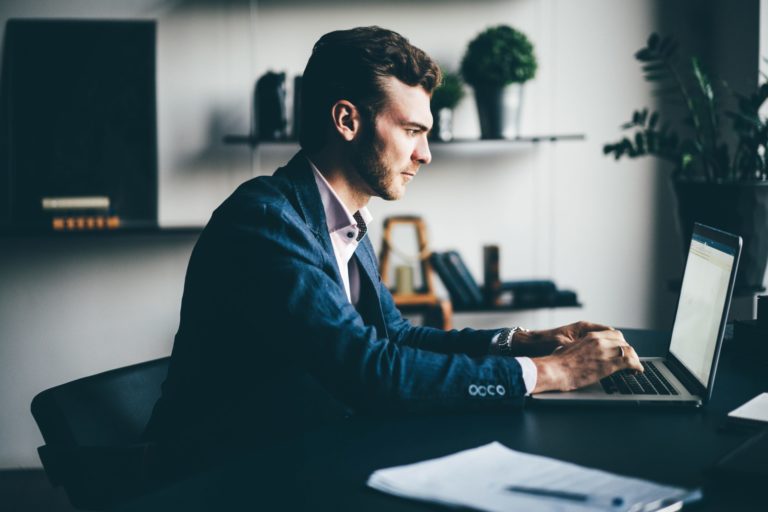 a person sitting at a desk using a laptop