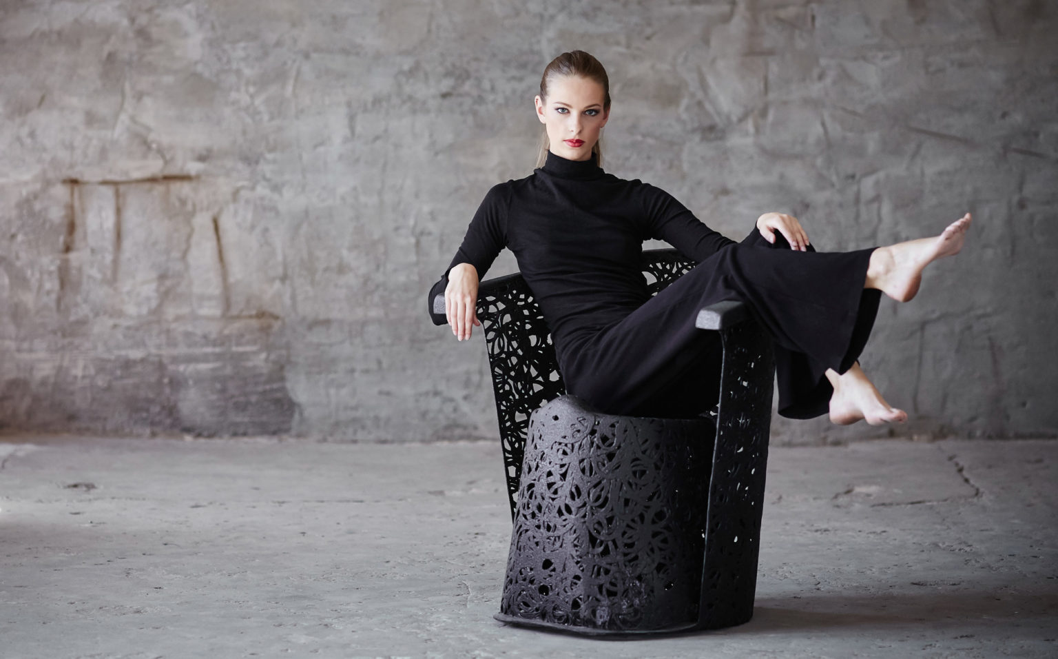 A woman in a black clothes sitting on a chair.