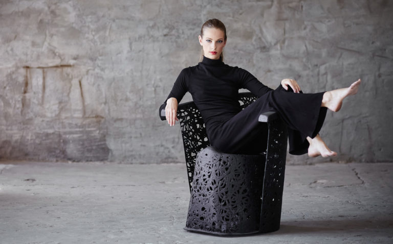 A woman in a black clothes sitting on a chair.