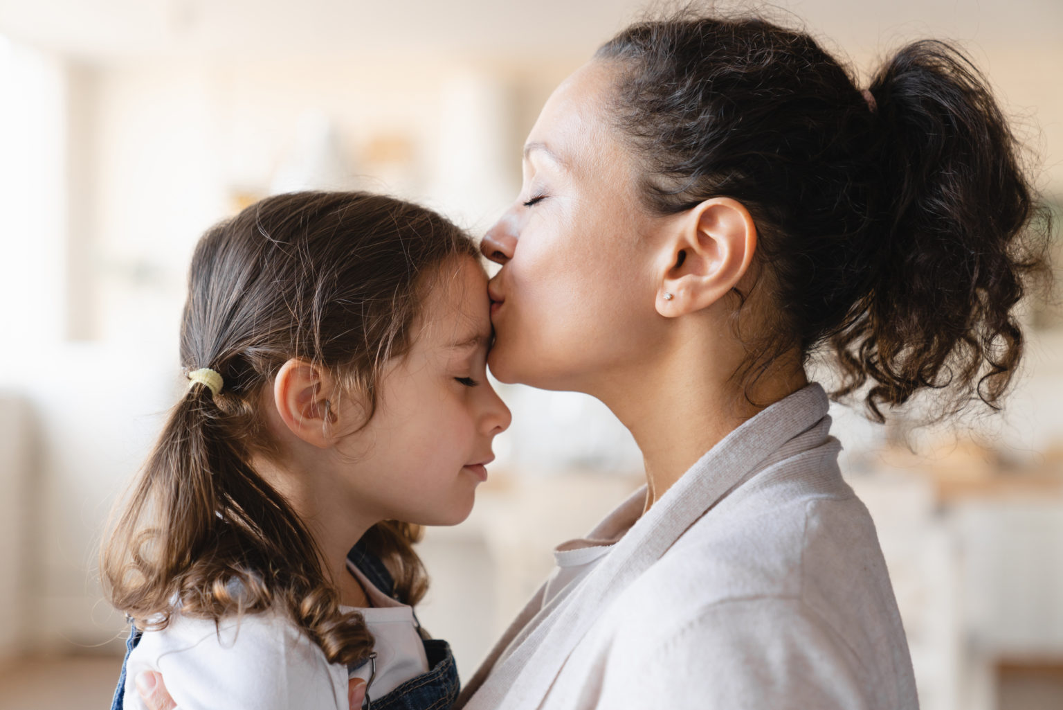 Mother kissing hugging embracing her small little daughter. Motherhood, parenthood, love and family